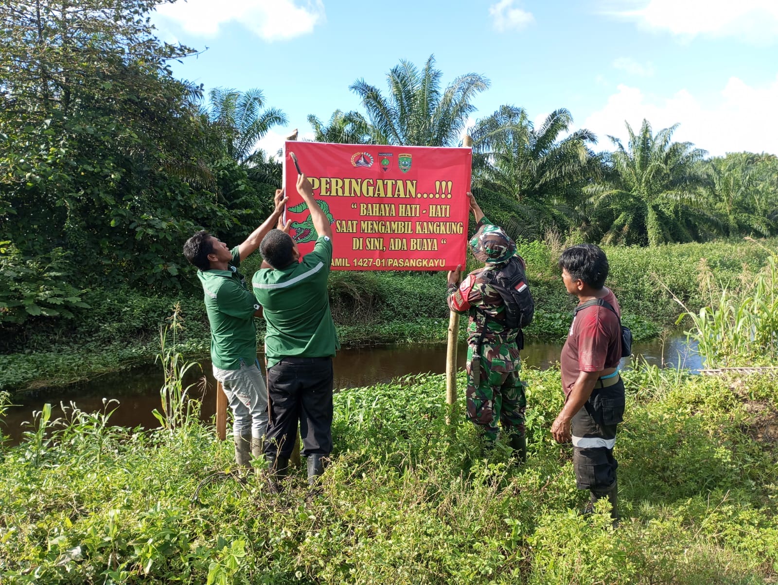 Peduli Keselamatan Warga, Babinsa Koramil Pasangkayu Memasang Papan Himbauan Daerah Rawan Buaya